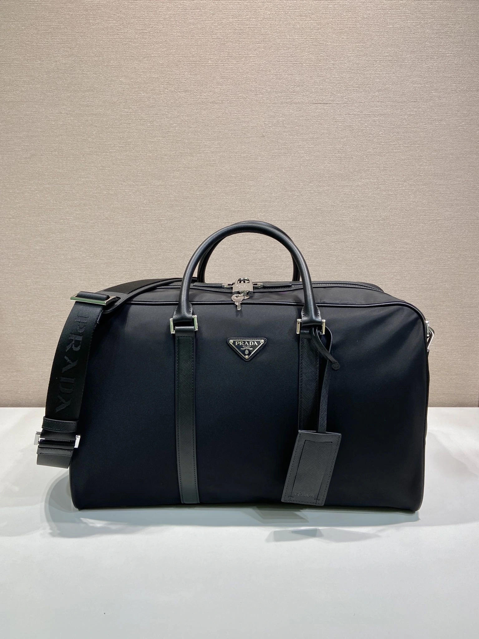 🎉新作トラベルバッグ🎉2VC014 Sサイズ🎉🎉 このRe-Nylon(再生ナイロン)製のトラベルバッグは、美しいサフィアーノレザーの縁取りが施され、モダンでエレガントな魅力を放っています。取り外し可能なショルダーストラップで肩掛けも便利で、象徴的な金属製の三角ロゴがブランドのスタイルを際立たせています。大容量で軽量かつ実用的、旅行に欠かせないアイテムです🎉