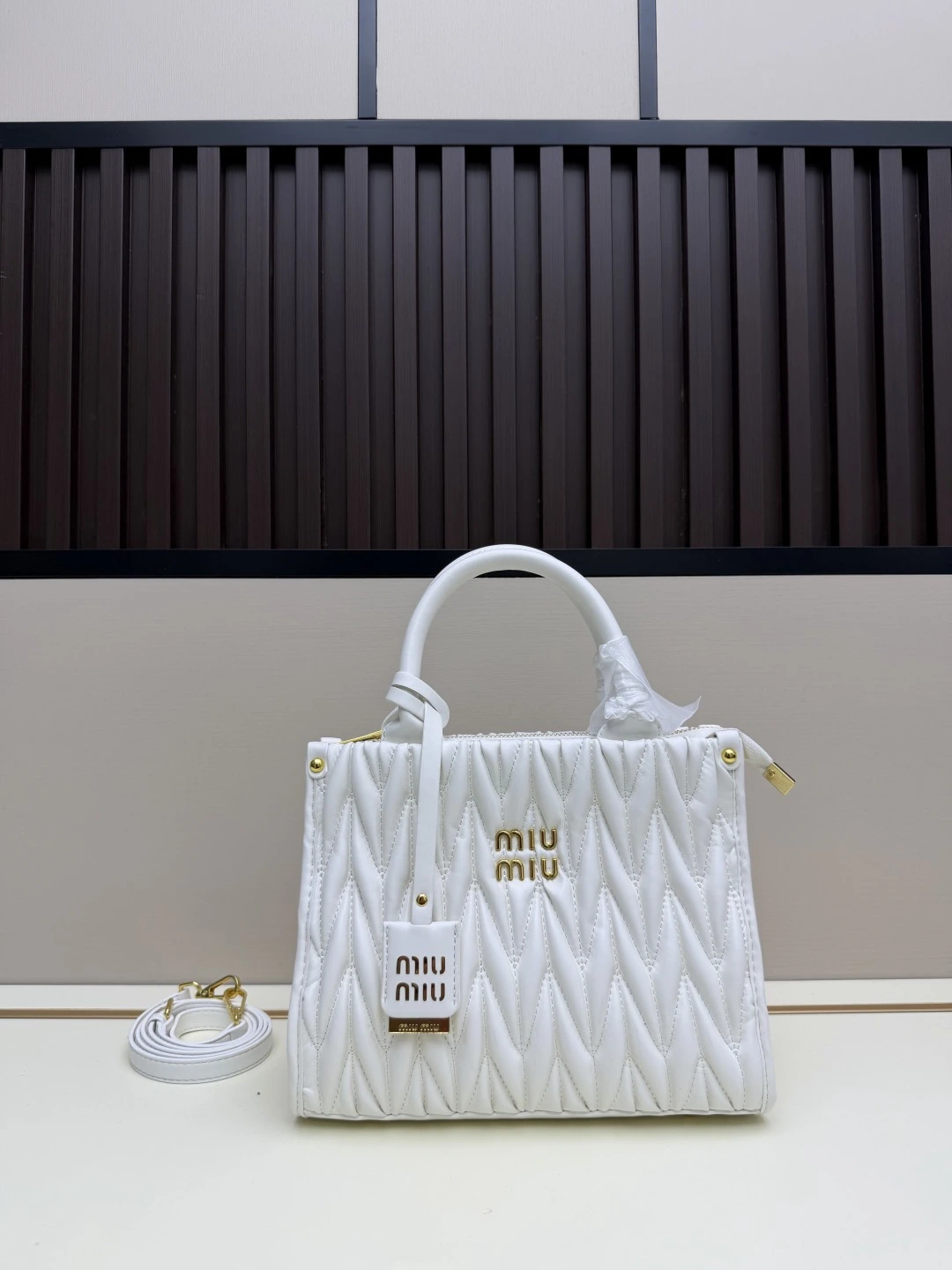 Miu Miu 新作トートバッグ。華やかなマテラッセ技法により、柔らかなラムレザーのトートバッグに活気と汎用性の高い都会的なシルエットを再解釈。バッグ本体に質感豊かな立体的なテクスチャーを与え、レトロなマット仕上げの金具、新しいロゴチャーム、レザーハンドル、取り外し可能なショルダーストラップ、内ポケットが、機能性とモダンさを兼ね備えたデザインを形作っています
