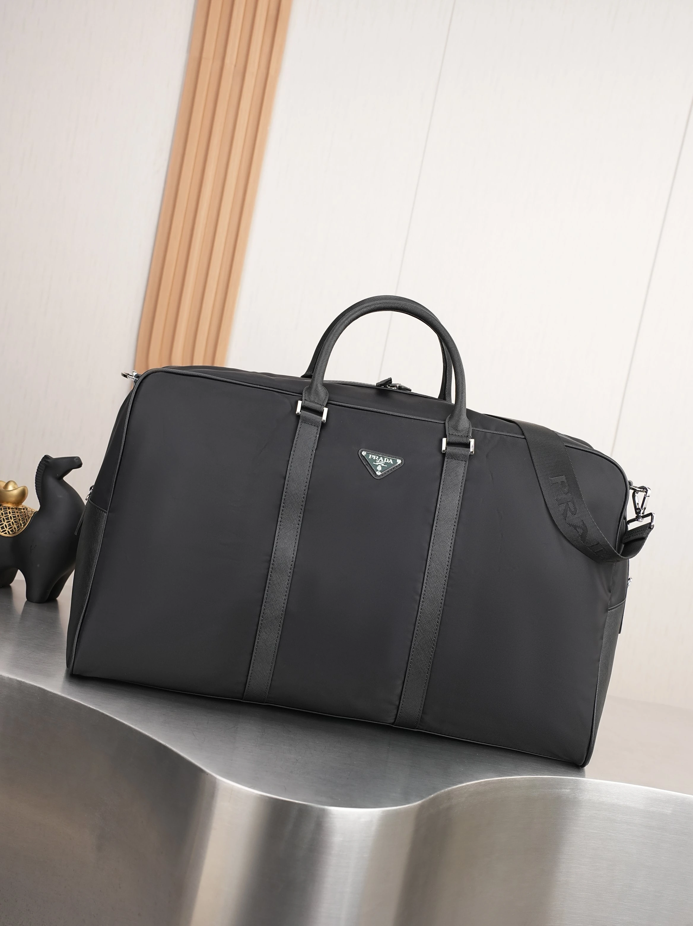 ラージサイズ🎉新作トラベルバッグ🎉🎉🎉 このRe-Nylon(再生ナイロン)製のトラベルバッグは、美しいサフィアーノレザーの縁取りが施され、モダンでエレガントな魅力を放っています。取り外し可能なショルダーストラップで肩掛けも便利で、象徴的な金属製の三角ロゴがブランドの風格を際立たせています。大容量で軽量かつ実用的、旅行に欠かせないアイテムです🎉🎉型番:201