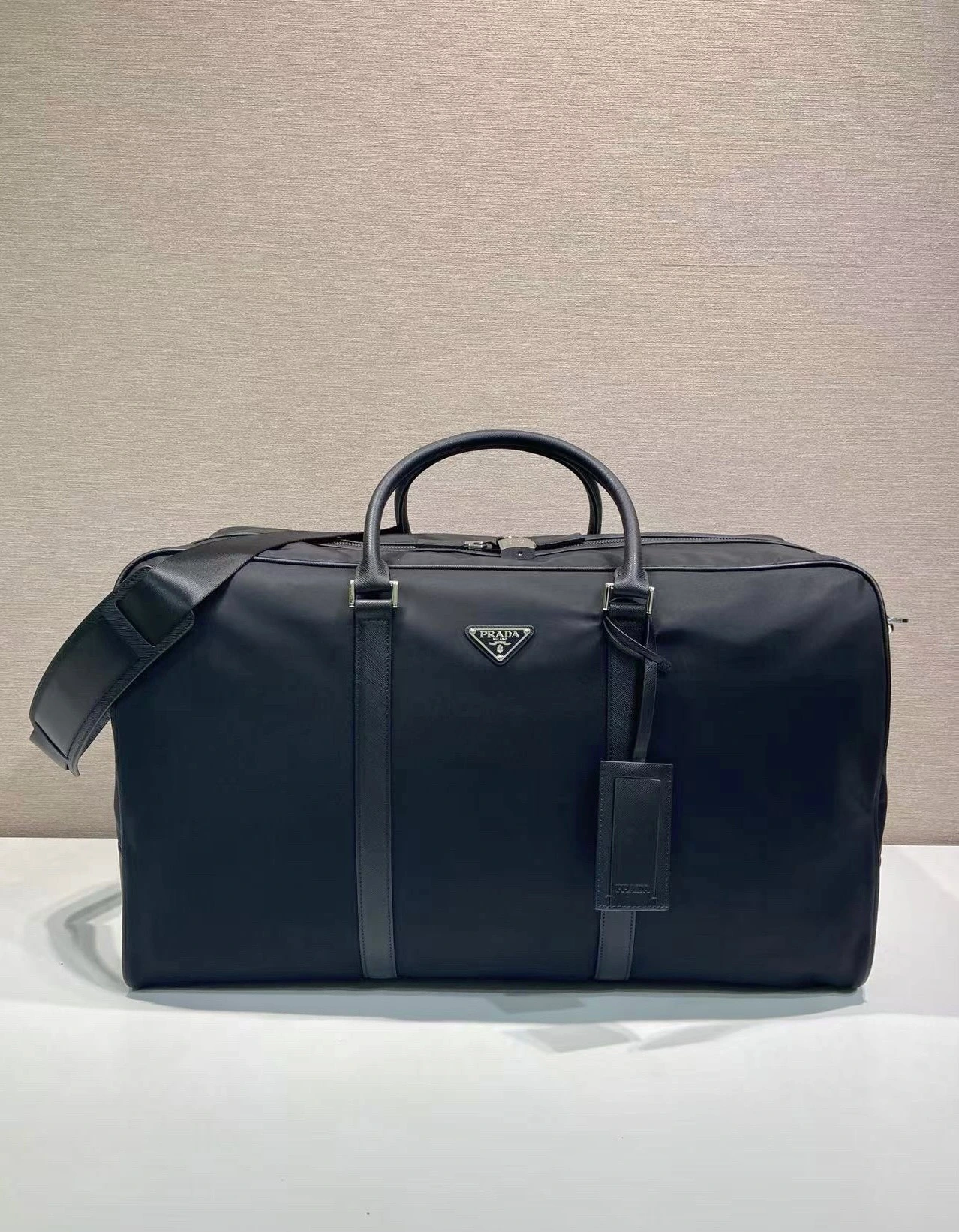 🎉新作トラベルバッグ🎉2VC013🎉🎉 このRe-Nylon(再生ナイロン)製のトラベルバッグは、美しいサフィアーノレザーの縁取りが施され、モダンでエレガントな魅力を放っています。取り外し可能なショルダーストラップで肩掛けも便利で、象徴的な金属製の三角ロゴがブランドのスタイルを際立たせています。大容量で軽量かつ実用的、旅行に欠かせないアイテムです🎉🎉 幅55
