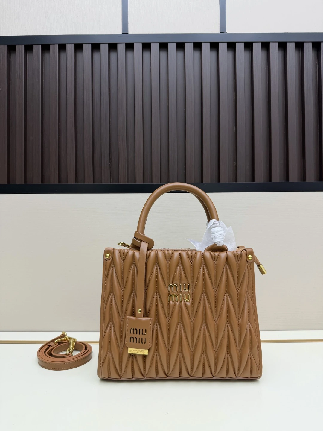 Miu Miu 新作トートバッグ。華やかなマテラッセ技法により、柔らかなラムレザーのトートバッグに活気と汎用性の高い都会的なシルエットを再解釈。バッグ本体に質感豊かな立体的なテクスチャーを与え、レトロなマット仕上げの金具、新しいロゴチャーム、レザーハンドル、取り外し可能なショルダーストラップ、内ポケットが、機能性とモダンさを兼ね備えたデザインを形作っています