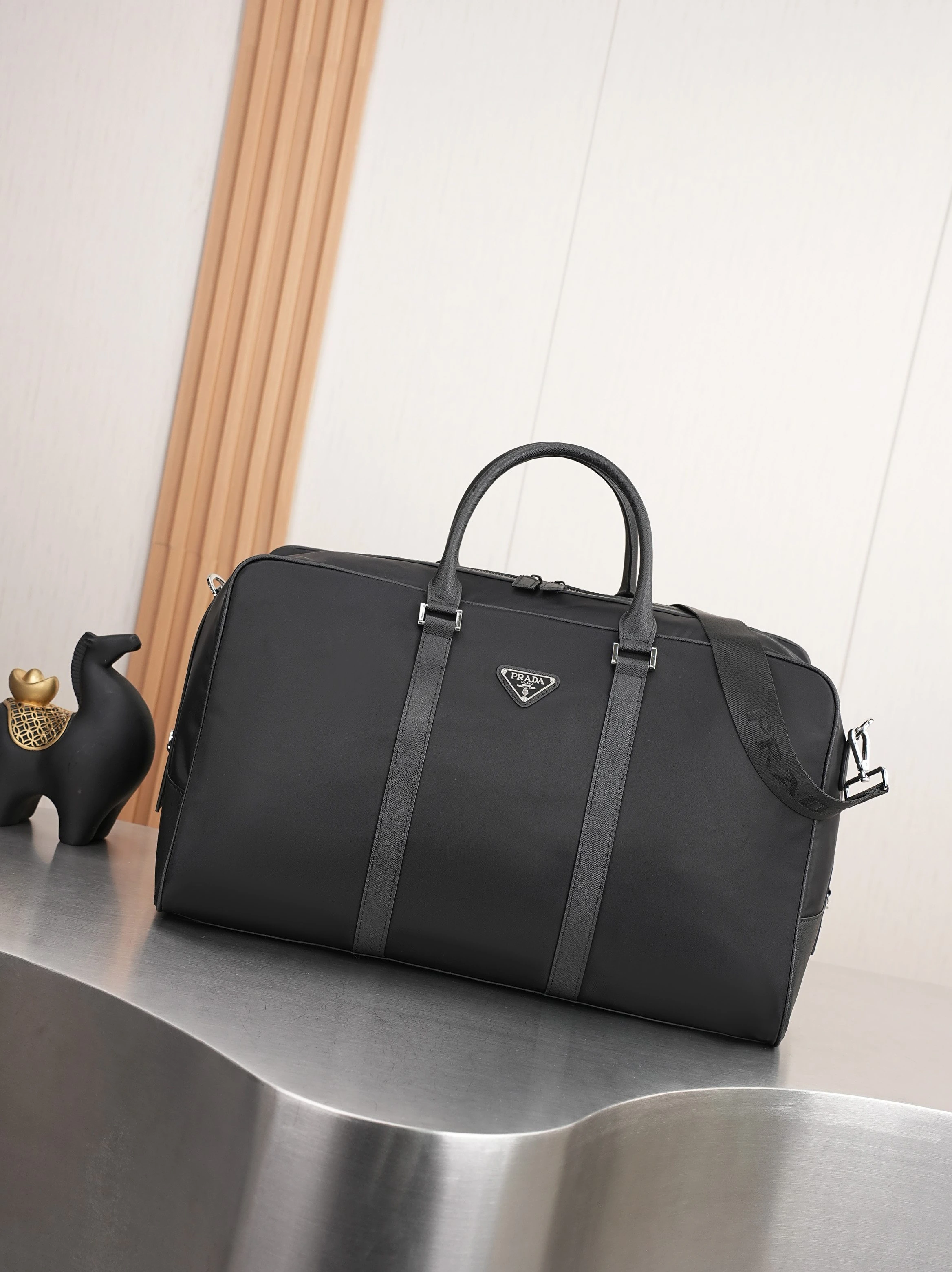 スモールサイズ🎉新作トラベルバッグ🎉🎉🎉 このRe-Nylon(再生ナイロン)製のトラベルバッグは、美しいサフィアーノレザーの縁取りが施され、モダンでエレガントな魅力を放っています。取り外し可能なショルダーストラップで肩掛けも便利で、象徴的な金属製の三角ロゴがブランドの風格を際立たせています。大容量で軽量かつ実用的、旅行に欠かせないアイテムです🎉🎉型番:20