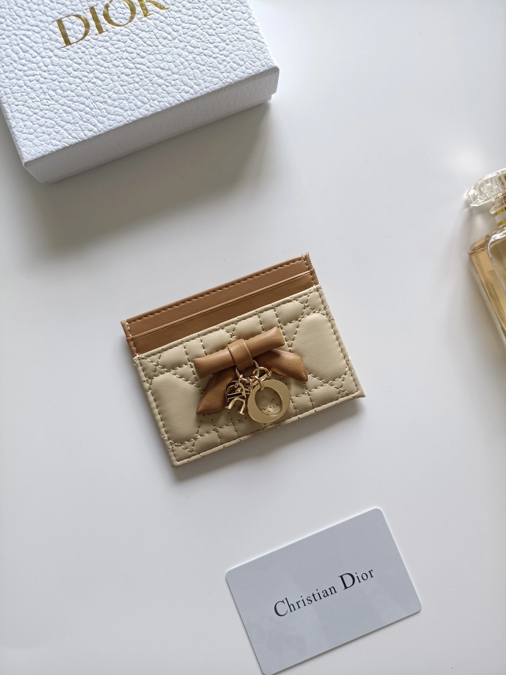 ディオールの最新作、商品番号:S2604 サイズ:10.5×8×0.5cm この「Lady Dior Freesia」カードケースは、エレガントで実用的なアクセサリーです。淡いピンク(Soupir pink)とクリーム色のツートンカラーで、ラムレザーを丁寧に仕立て、カギ目模様のステッチが施されています。前面には装飾用のレザーリボンがアクセントとしてあしらわれ
