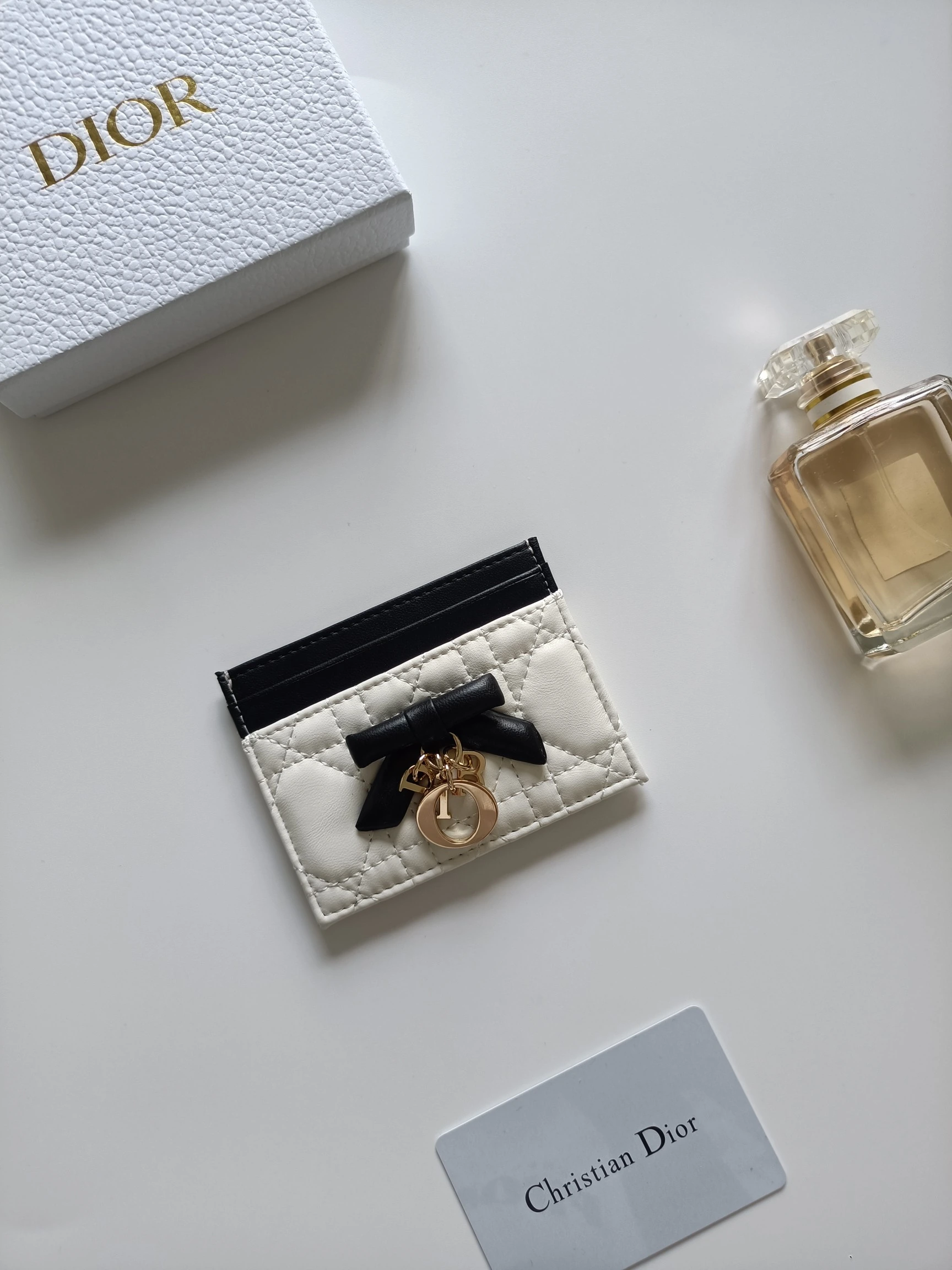 ディオールの最新作、商品番号:S2604 サイズ:10.5×8×0.5cm この「Lady Dior Freesia」カードケースは、エレガントで実用的なアクセサリーです。淡いピンク(Soupir pink)とクリーム色のツートンカラーで、ラムレザーを丁寧に仕立て、カギ目模様のステッチが施されています。前面には装飾用のレザーリボンがアクセントとしてあしらわれ
